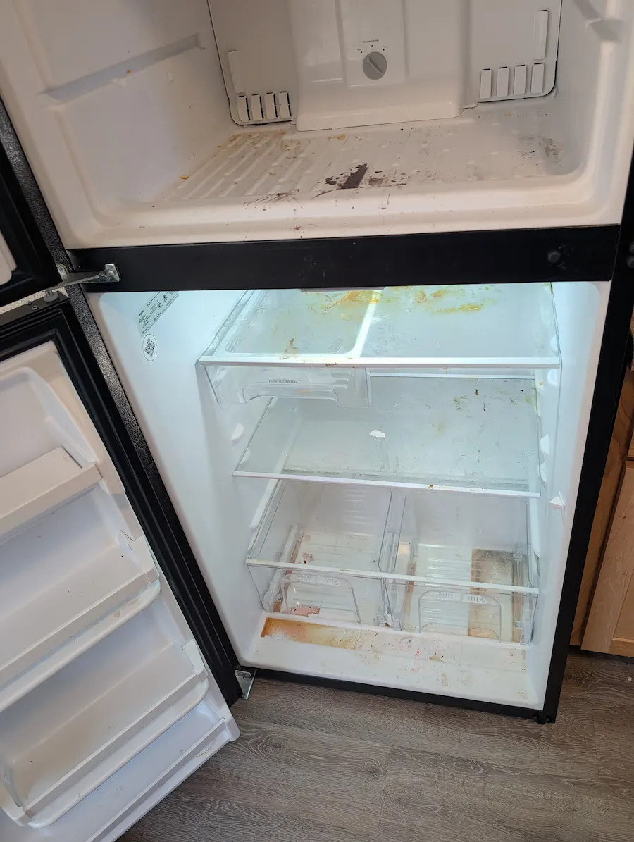 Refrigerator interior with food spills, dirty shelves, and built-up grime before deep cleaning in Fargo, ND